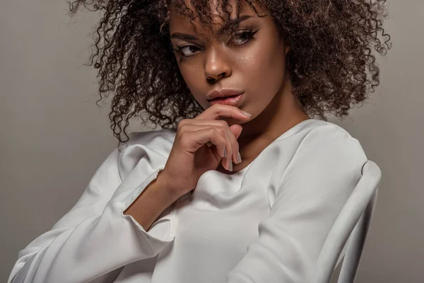 Молодая чувственная африканская американка в белой рубашке с пальцем на губах изолирована на сером фоне — стоковое фото