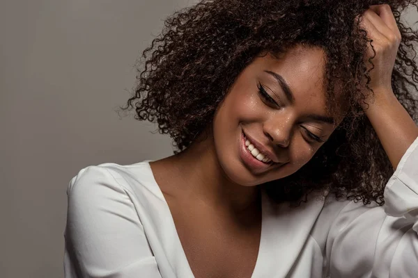 Young sensual african american woman in white shirt rests on the hand isolated on grey background — Stock Photo