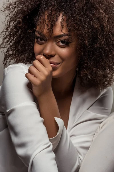 Belle femme afro-américaine en chemise blanche souriante et regardant la caméra isolée sur fond gris — Photo de stock