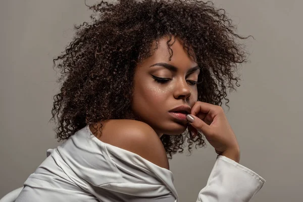 Jovem mulher americana africana atraente em camisa branca tocando lábios isolados em fundo cinza — Fotografia de Stock