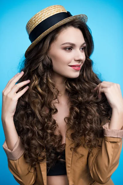 Atractiva mujer joven con pelo rizado largo en sombrero canotier y chaqueta - foto de stock