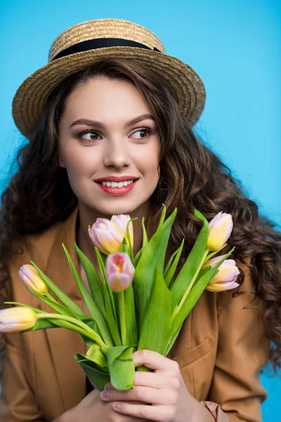Feliz joven mujer en canotier sombrero y chaqueta celebración ramo de hermosos tulipanes - foto de stock