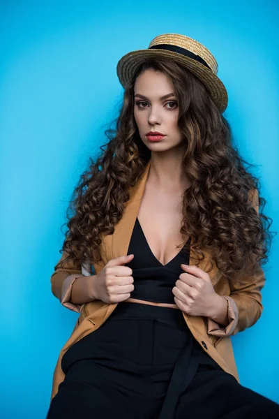 Seductora joven en elegante sombrero canotier y chaqueta aislada en azul - foto de stock