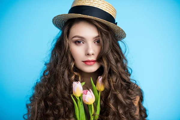 Atractiva mujer joven con pelo largo rizado en sombrero canotier celebración de hermosos tulipanes - foto de stock