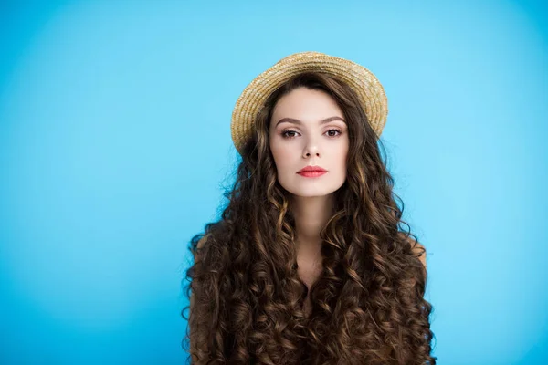 Beautiful young woman in canotier hat on long curly hair isolated on blue — Stock Photo