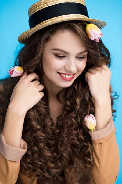 Atractiva joven en sombrero canotier con flores en su largo pelo rizado - foto de stock