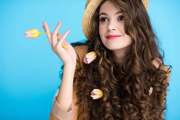 Lächelnde junge Frau mit Kanuhut und Blumen im langen lockigen Haar — Stockfoto