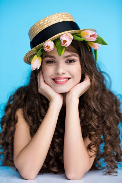 Sonriente joven en sombrero canotier con tulipanes frescos debajo de ella - foto de stock