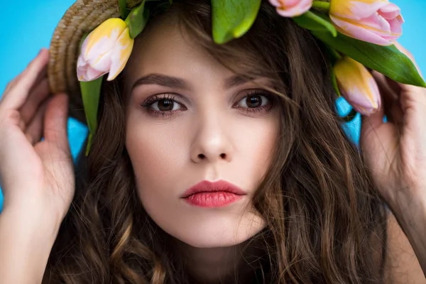 Young woman in canotier hat with beautiful tulips under it looking at camera — Stock Photo