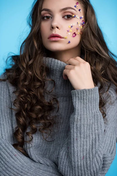 Elegante giovane donna dai capelli lunghi con fiori sul viso in maglione — Foto stock