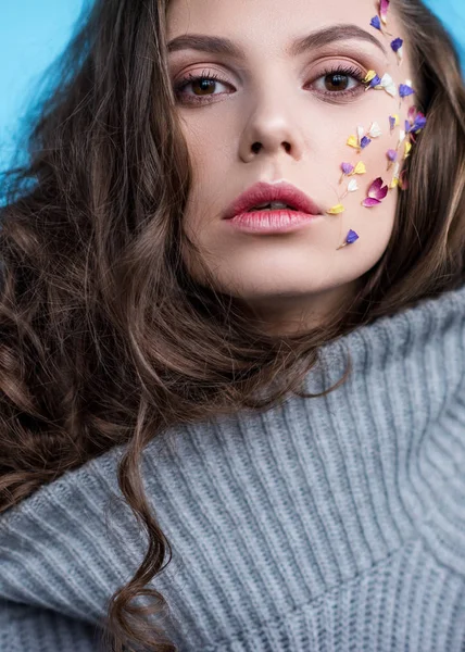 Nahaufnahme Porträt einer Frau im warmen grauen Pullover mit Blumen am Gesicht — Stockfoto