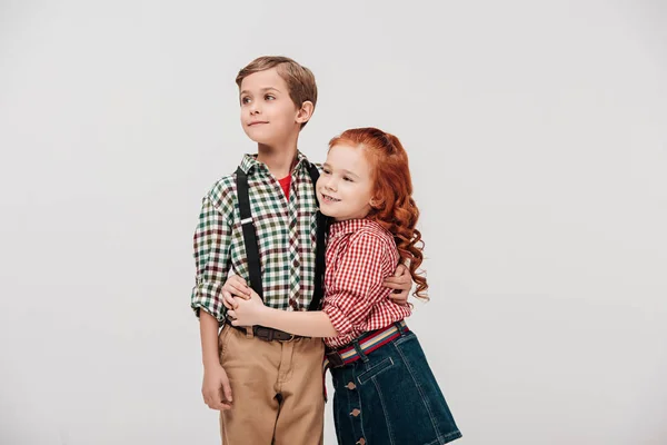 Lindos niños pequeños abrazando y mirando hacia otro lado aislados en gris - foto de stock