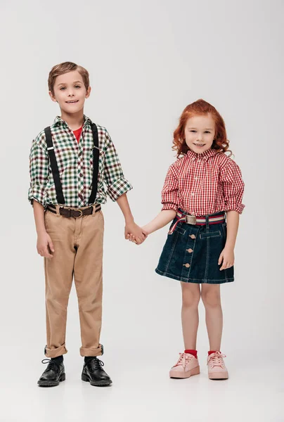 Entzückende kleine Kinder, die sich an den Händen halten und vereinzelt in die Kamera lächeln — Stockfoto