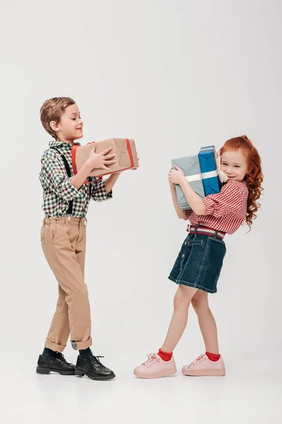 Adorable little kids holding colorful gift boxes isolated on grey — Stock Photo