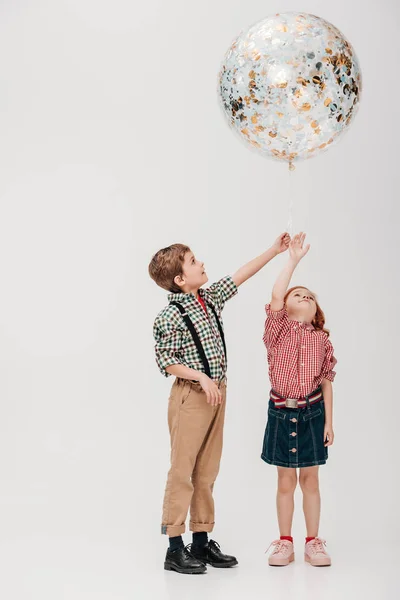 Entzückende kleine Kinder halten glänzende Luftballons isoliert auf grau — Stockfoto