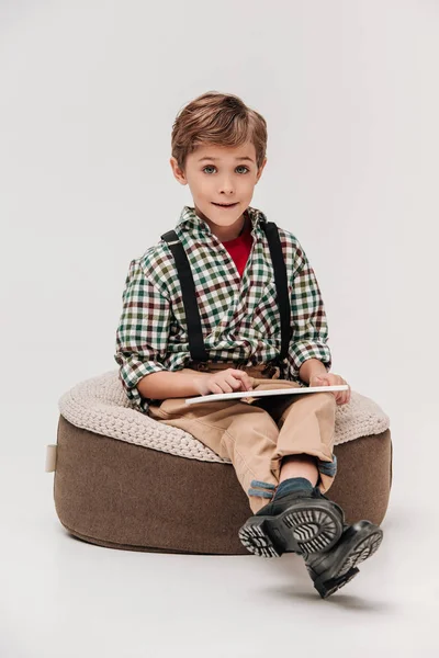 Netter kleiner Junge mit digitalem Tablet und lächelt in Kamera isoliert auf grau — Stockfoto