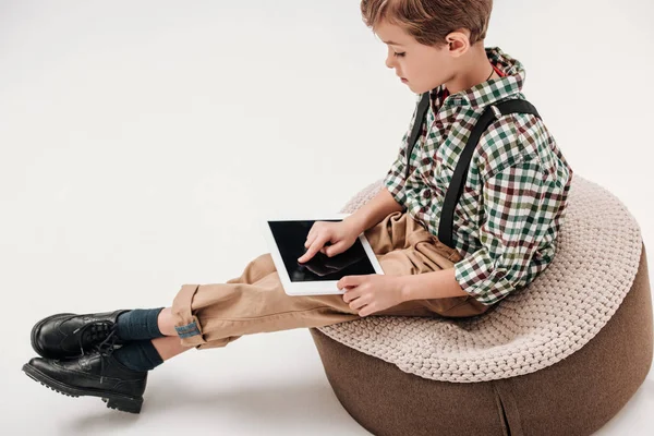 Вид сбоку маленького мальчика, сидящего и использующего цифровую табличку с экраном, изолированным на сером фоне — стоковое фото