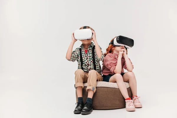 Niedlichen kleinen Kindern sitzen und mit Virtual-Reality-Headsets isoliert auf grau — Stock Photo