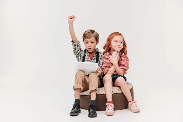 Entzückende kleine Kinder mit digitalen Geräten isoliert auf grau — Stockfoto