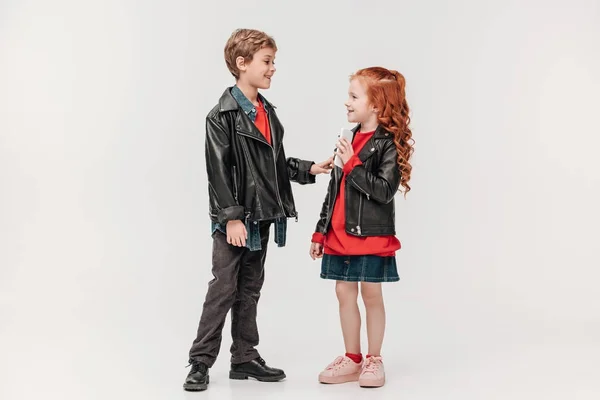 Adorable stylish little kids couple with smartphone isolated on grey — Stock Photo