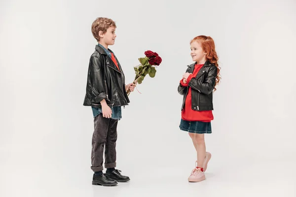 Menino apresentando buquê de rosas para sua linda namoradinha isolada em cinza — Fotografia de Stock