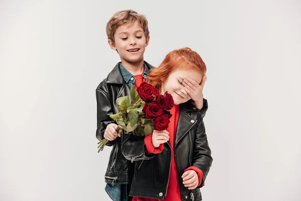 Menino feliz apresentando buquê de rosas para sua namoradinha isolada em cinza — Fotografia de Stock