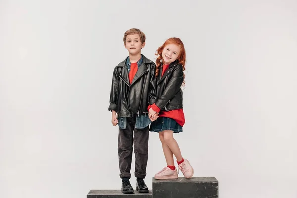 Adorables niños tomados de la mano en escaleras aisladas en gris - foto de stock