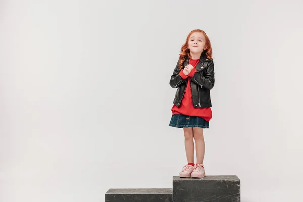 Adorable petite fille en veste en cuir sur boîte en bois isolé sur gris — Photo de stock