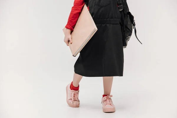 Cropped shot of schoolgirl in black dress with big book isolated on grey — Stock Photo