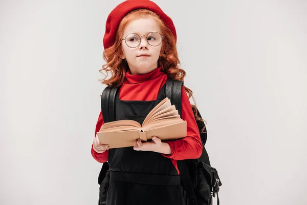 Pensativa colegiala con libro aislado en gris - foto de stock