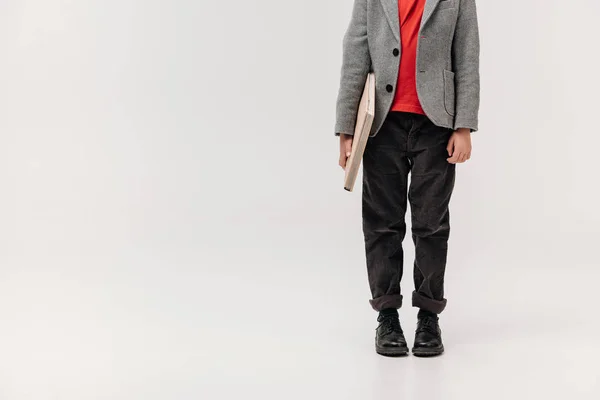 Cropped shot of stylish little schoolboy with big book isolated on grey — Stock Photo