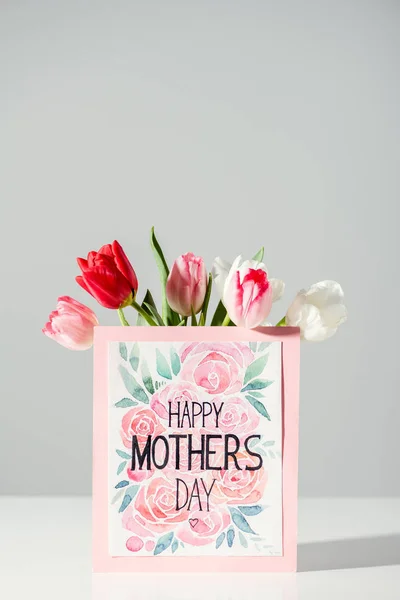 Happy mothers day greeting card and beautiful blooming tulips on grey — Stock Photo