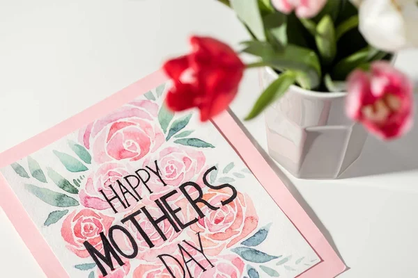 Close-up view of happy mothers day card and tulips in vase on white — Stock Photo