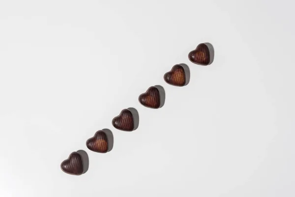 Vista superior de deliciosos caramelos en forma de corazón de chocolate aislados en gris - foto de stock