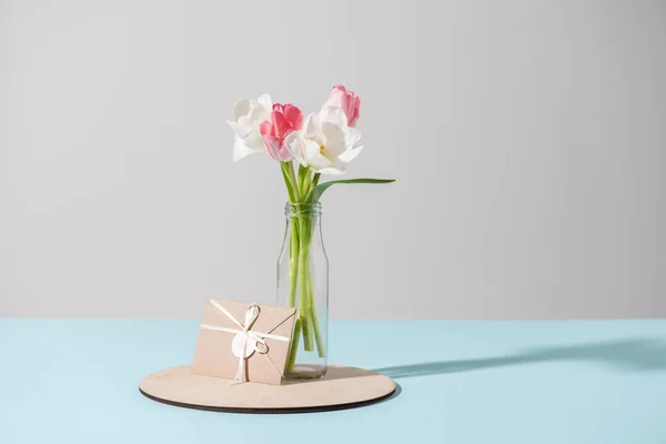 Belles fleurs de tulipes en bouteille et enveloppe en verre — Photo de stock