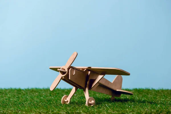 Vista de cerca de un pequeño avión de juguete de madera sobre hierba verde - foto de stock