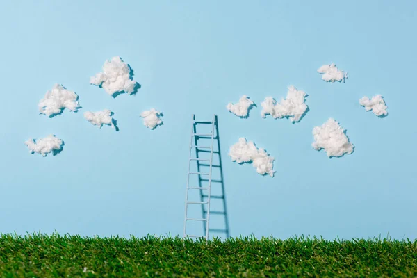 Small ladder standing on green grass and blue sky with clouds — Stock Photo