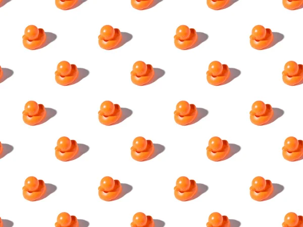 Nahtloses Muster niedlicher orangefarbener Gummi-Enten mit Schatten auf Weiß — Stockfoto