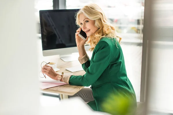 Selektiver Fokus der schönen Geschäftsfrau, die am Arbeitsplatz per Smartphone spricht — Stockfoto