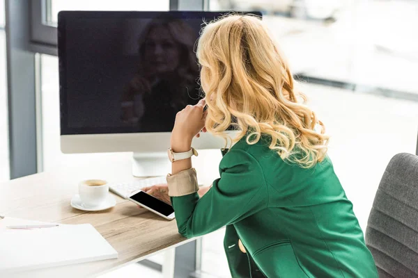 Femme d'affaires utilisant un smartphone et un ordinateur de bureau avec écran blanc sur le lieu de travail — Photo de stock