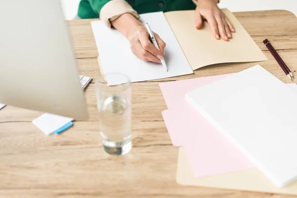 Teilansicht einer Geschäftsfrau, die Papierkram am Arbeitsplatz erledigt — Stockfoto