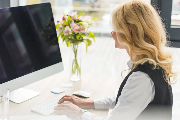 Atractiva mujer de negocios madura utilizando la computadora de escritorio en el lugar de trabajo - foto de stock