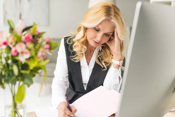 Geschäftsfrau mittleren Alters erledigt Papierkram am Arbeitsplatz — Stockfoto