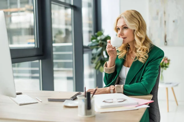 Mujer de negocios beber café y el uso de la computadora de escritorio en el lugar de trabajo - foto de stock