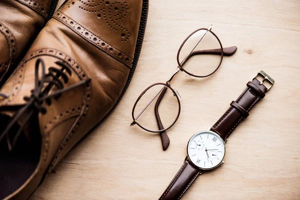 Vista superior sapatos castanhos, óculos e relógio na superfície de madeira — Fotografia de Stock