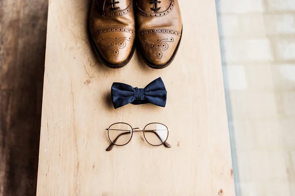 Высокий угол обзора обуви, галстук лук и очки на деревянный стенд — стоковое фото