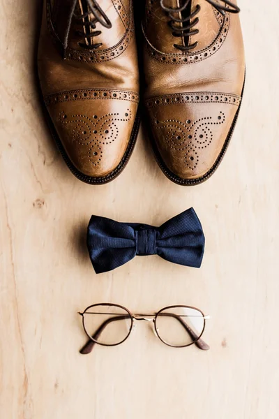 Vista dall'alto di scarpe, papillon e occhiali sul pavimento in legno — Foto stock