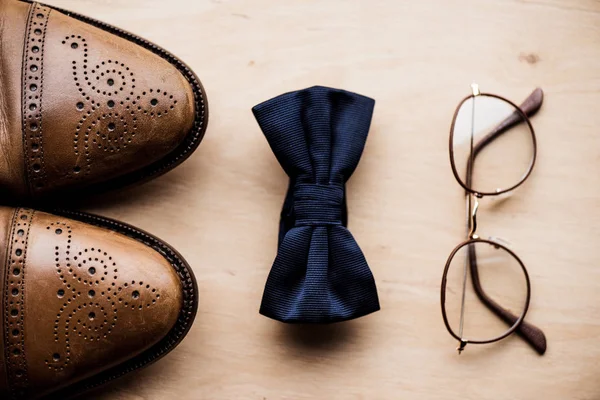 Vista dall'alto di scarpe, papillon e occhiali su superficie di legno — Foto stock