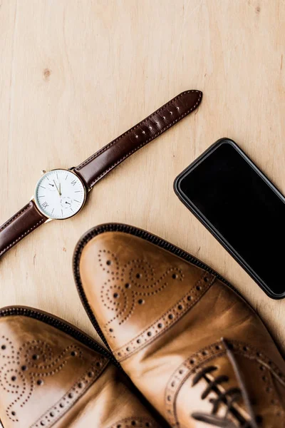 Vista dall'alto di orologio, smartphone e scarpe su tavolo in legno — Foto stock