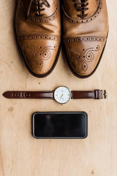 Vista superior de los zapatos, smartphone y reloj en la superficie de madera - foto de stock